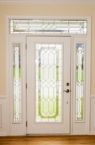An inside view of a white entry door with decorative glass, sidelites, and a transom. 