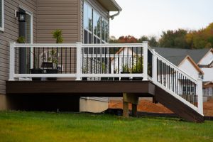 An image of a brown wood deck with a white railing attached to a single-family home.